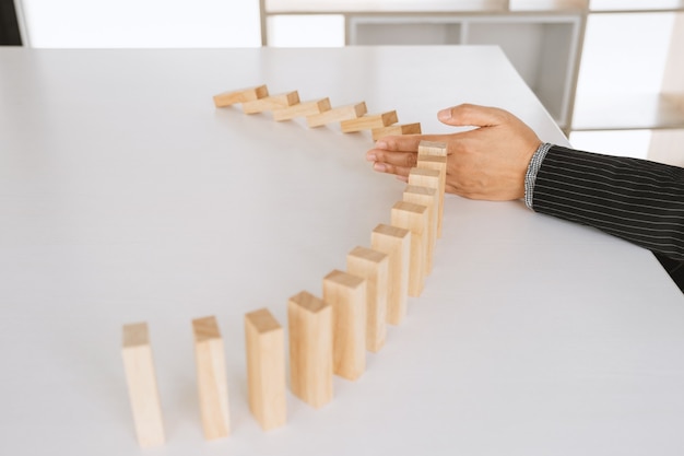 Woman hand stop wooden blocks for protect other block Concept Risk of management and strategy plan