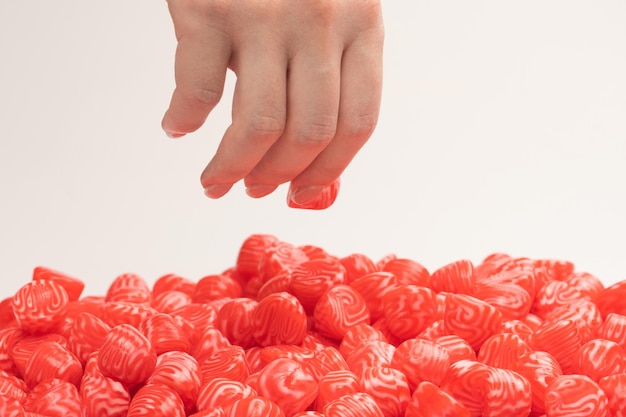 Woman hand takes a jelly candy on white background