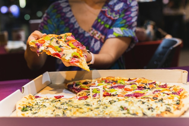 Woman hand taking a slice of New York pizza in takeaway box