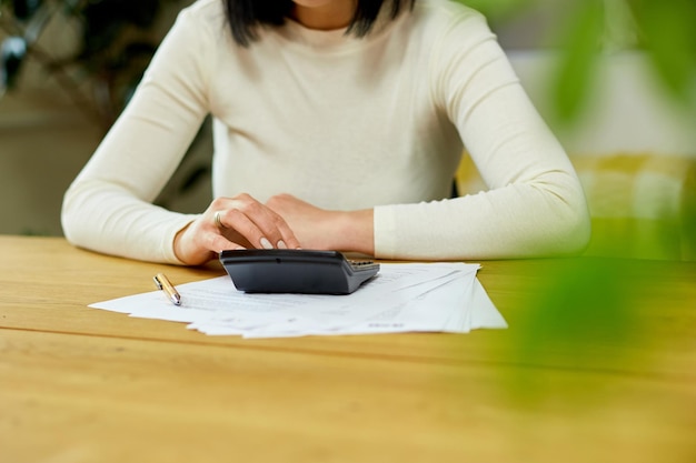 Woman hand using calculator for calculate domestic bills at home