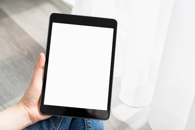 Woman hand using digital tablet on the table and the screen is blank.