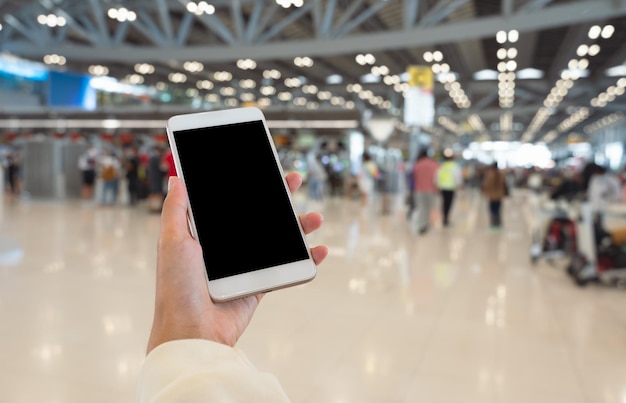 Woman hand using smart phone with blurred airport terminal background