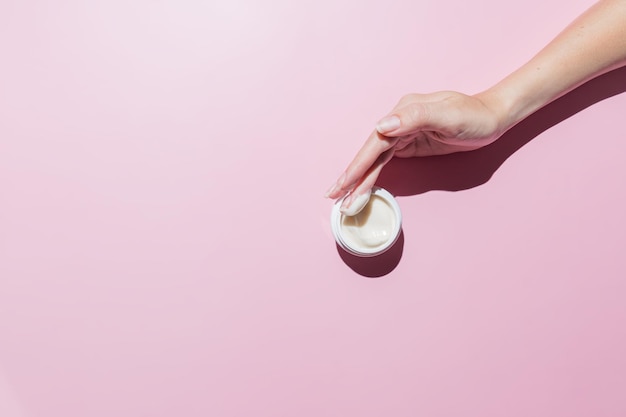 Woman hand with a cream on on a pink background Groomed hands natural short nails mockup cosmetics