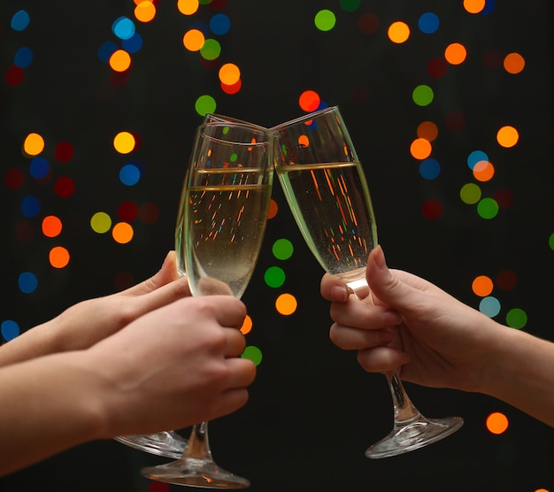 Woman hand with glasses of champagne on garland background