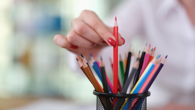 Woman hand with pulls out red pencil in office closeup