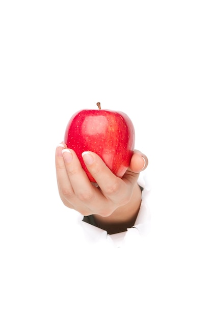 Woman hand with red apple through a hole in paper isolated on white background