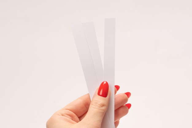 Woman hand with red nails with test strips for the perfume isolated on a white background