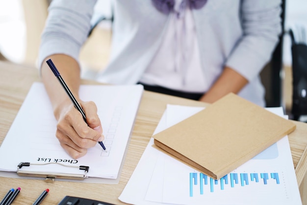 Woman hand writing check list paper, memo planning concept. Paperwork for filling in information in business.