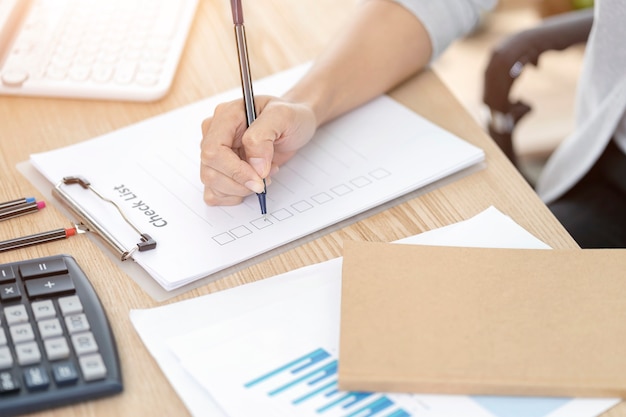 Woman hand writing check list paper, memo planning concept. Paperwork for filling in information in business.