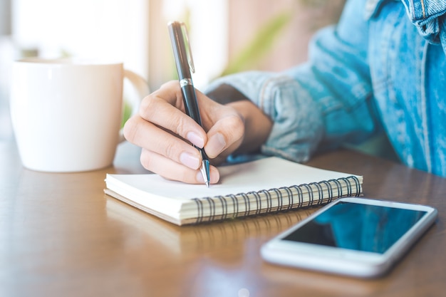 Woman hand writing on a notepad with a pen