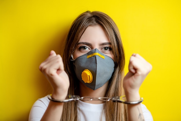 Woman in handcuffs wearing respirator mask