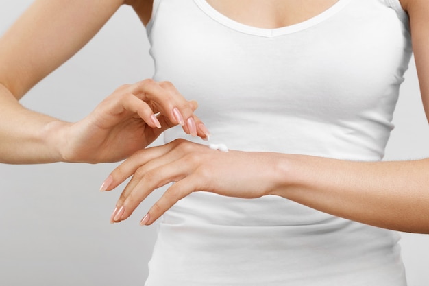 woman hands applying moisturizing cream to skin