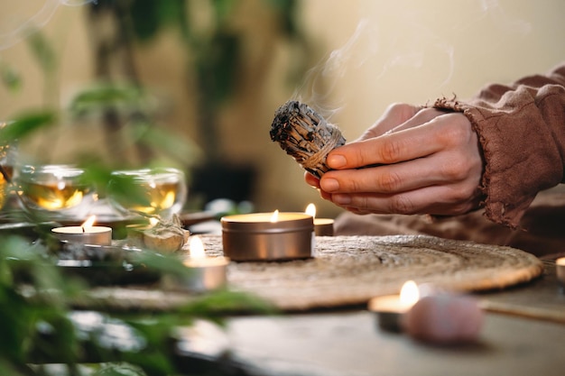 Woman hands burning white sage before ritual on cadle