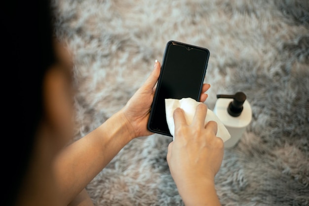 Woman hands cleaning phone screen with alchohol at home