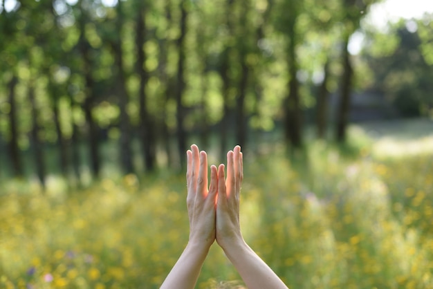 Woman hands in connection with nature doing yoga outdoors