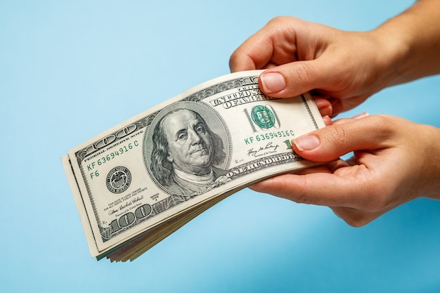 Woman hands counting dollar banknotes on blue 