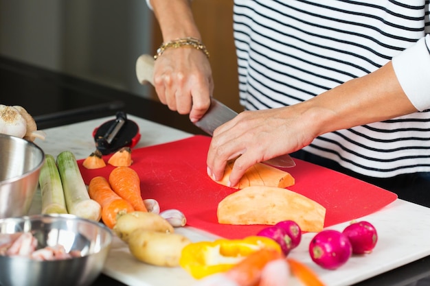 Woman hands cutting slicing vegetables on a cutting board