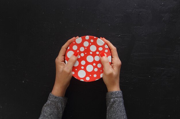 Woman hands give valentine or other holiday handmade present in paper with red ribbon