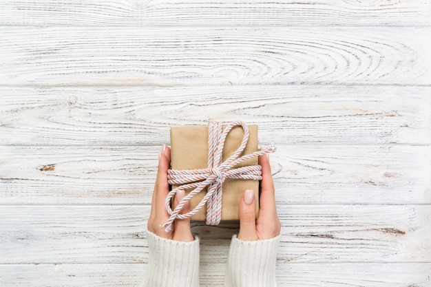 Woman hands give wrapped valentine or other holiday handmade present in paper with pink ribbon