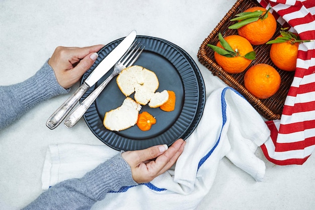 woman hands holding black ceramic plate with Fresh ripe mandarine