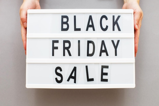 Woman hands holding black friday sale announcement on grey background