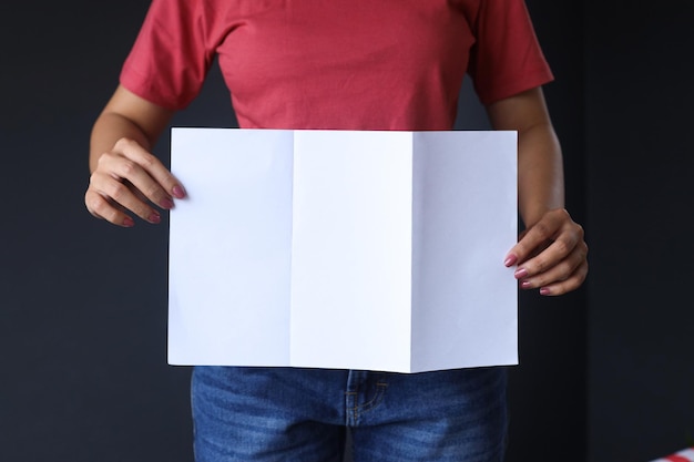 Woman hands holding blank opened tri fold flyer brochure on gray background as template for design p