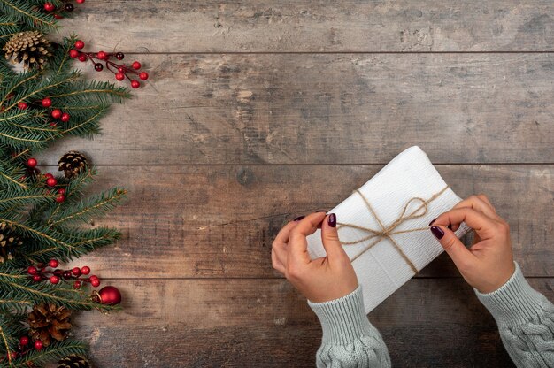 Woman hands holding christmas gift or present box decorated fir tree Cozy winter shot