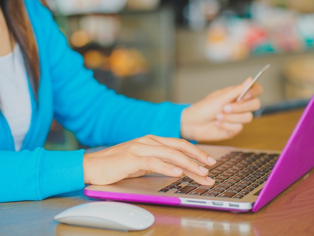 Woman hands holding a credit card and laptop computer for online shopping.