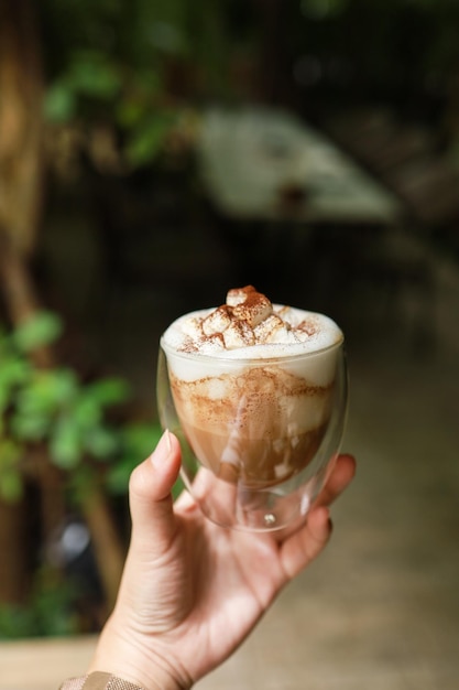 Woman hands holding cup of coffee with latte art holding cup of tea or coffee in the morning