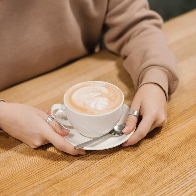 Woman hands holding a cup of hot cappuccino coffee in her hands