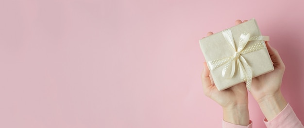 Woman hands holding gift box in palms on blue background, banner with copy space