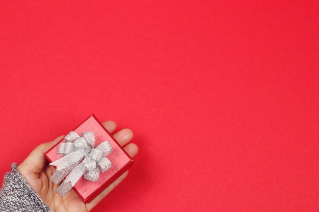 Woman hands holding gift box on red background. Happy new year concept. Valentines day bac