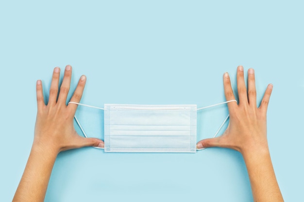 Woman hands holding a medical mask on a blue background