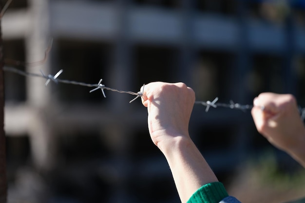 Woman hands holding metal security barbedwire fence