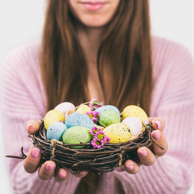 Woman hands holding painted easter egg in a small nest toned picture selective focus