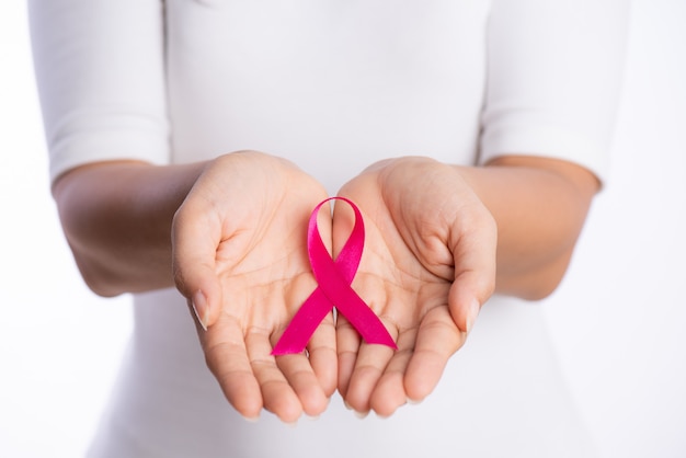 Woman hands holding pink breast cancer awareness ribbon on white