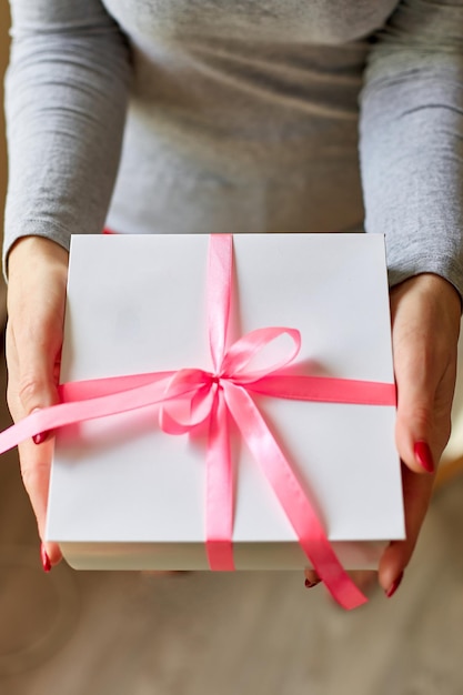 Woman hands holding a white present box with pink ribbon Female hands holding gift box Christmas hew year birthday Valentine xAday concept Copy space