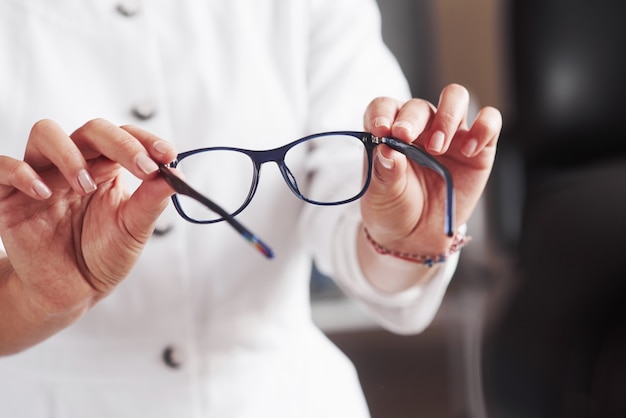 Woman hands holds the blue eyeglasses in the doctor cabinet.