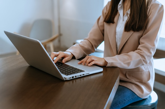 Woman hands is typing on a laptop and holding tablet at office