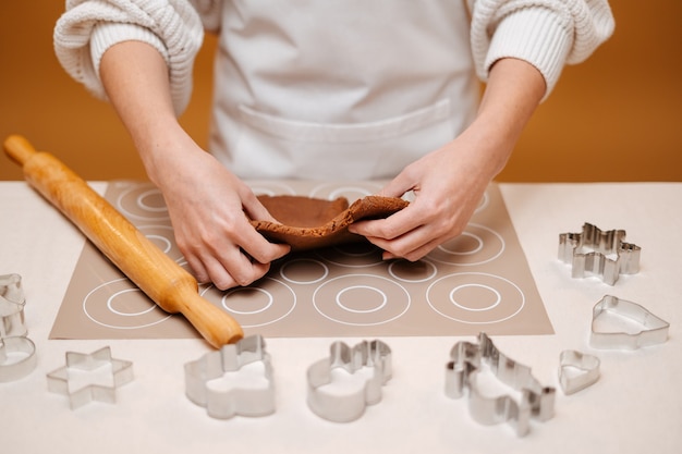 Woman hands kneading gingerbread dough for making christmas gingerbread using metal molds confection...