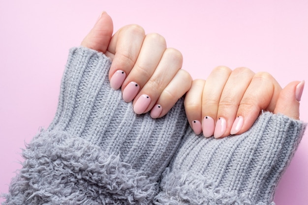 Woman hands in knitted gloves mitts with pink nude nails