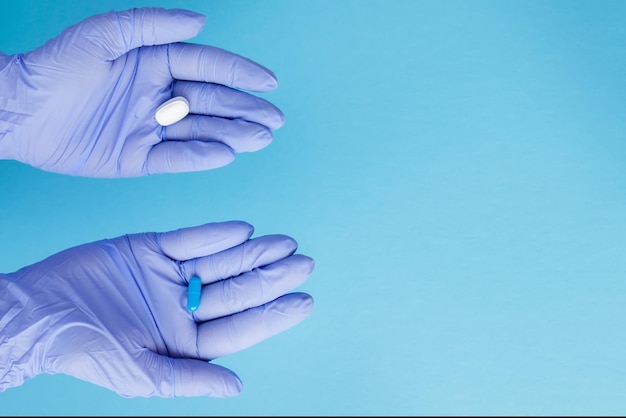 Woman hands in medical gloves giving two big pills Blue and white Make your selection Copy space