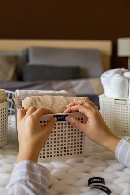 Woman hands neatly folded linens and towels use marie kondo method with sticky label tags