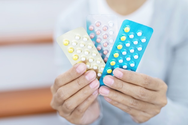 Woman hands opening birth control pills in hand. eating Contraceptive pill.