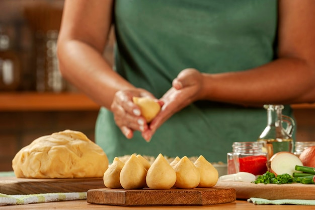 Woman hands preparing brazilian croquette coxinha de frango on a wooden table