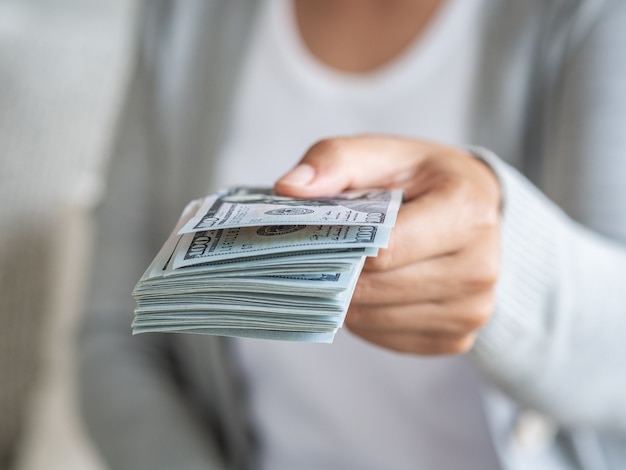 Woman hands proposing money us dollar bills to you.