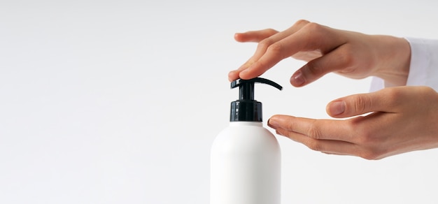 Woman hands pushing pump plastic soap bottle with copy space, using wash hand sanitizer gel pump dispenser. killing germs, bacteria and virus