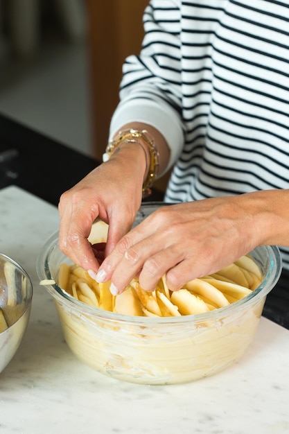 Woman hands putting apples while cooking apple pie