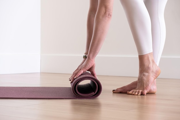 Woman hands rolling yoga mat in studio after practicing yoga workout