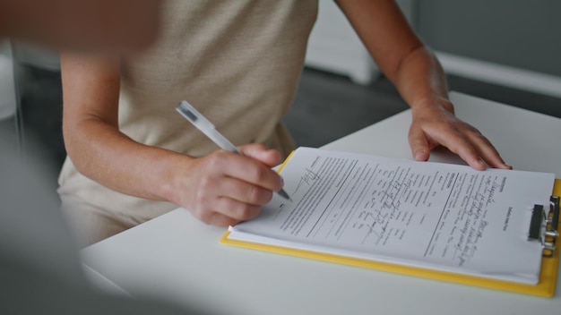 Woman hands signing papers sitting at table close up girl writing documents